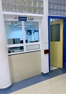 Clinic reception window beside a doorway with a blue frame.